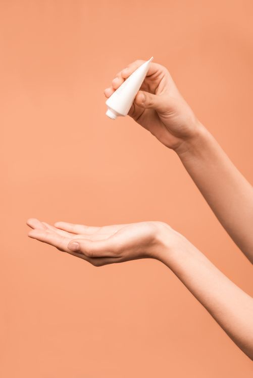 Blonde woman applying face cream and smiling