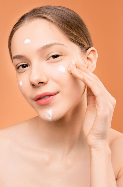 평온한 표정으로 페이셜 보습제를 바르는 젊은 여성의 클로즈업.