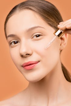 Close-up of a young woman using a dropper to apply facial serum for skincare treatment.