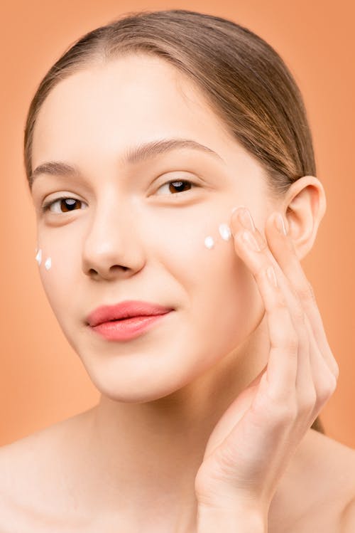 Free Woman With Pink Lipstick Applying Facial Cream Stock Photo