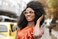 一位戴着太阳镜、穿着橙色连衣裙、在户外微笑的时尚女性的肖像