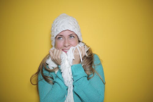 Portrait Photo of Woman in Blue Knit Sweater, White Knit Beanie, and White Scarf Smiling