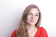 一个有雀斑的女人的肖像，在白色背景下穿着红色衬衫微笑