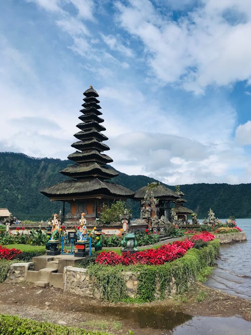 Traditional Asian pagoda on lake shore against cloudy blue sky