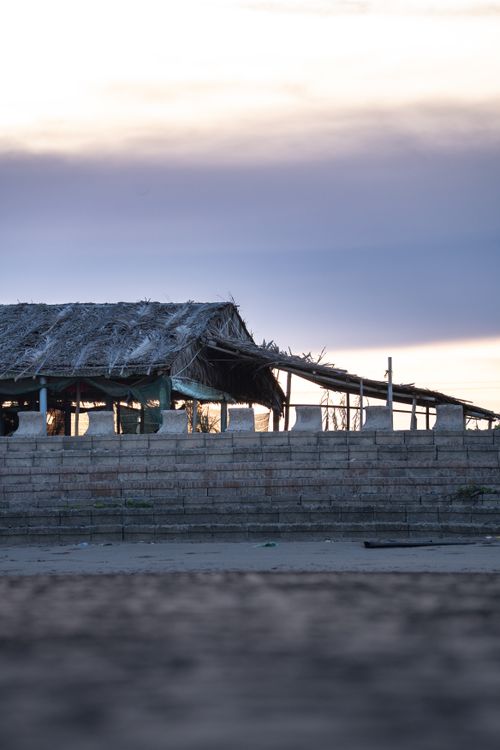 Free A rustic beach hut with a thatched roof against a twilight sky, creating a serene and calm atmosphere. Stock Photo