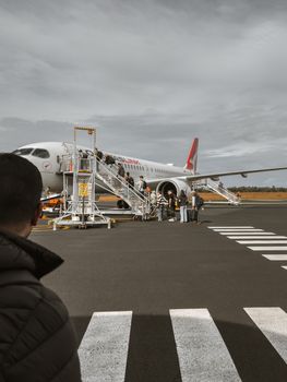 Passengers boarding a plane on a cloudy day at Coffs Harbour Airport, Australia.