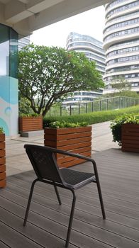 An empty chair on a patio, showcasing modern architecture and greenery for a serene urban escape.