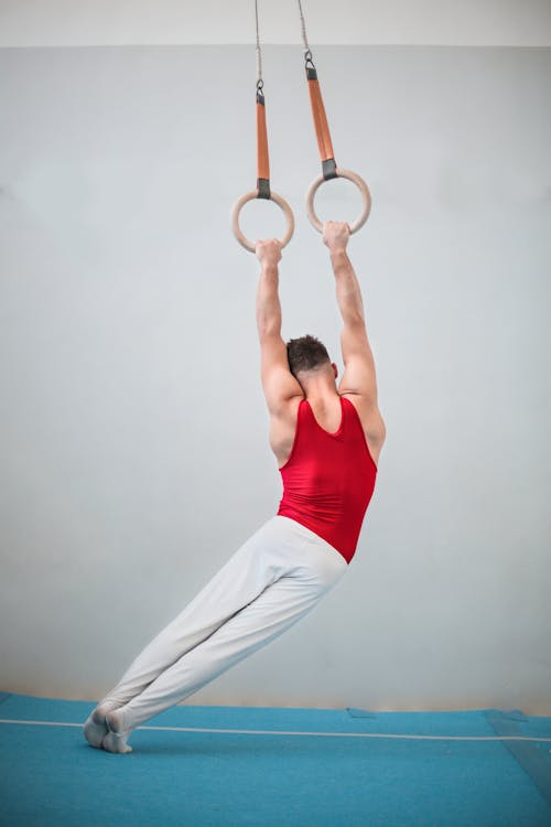 Foto De Vista Posterior Del Gimnasta Masculino Practicando En Anillos De Gimnasia