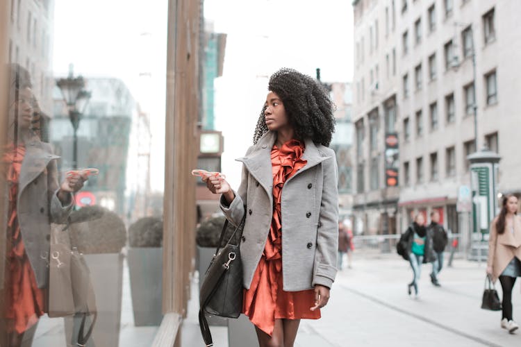 Selective Focus Photo Of Woman In Gray Coat Walking By Store Window