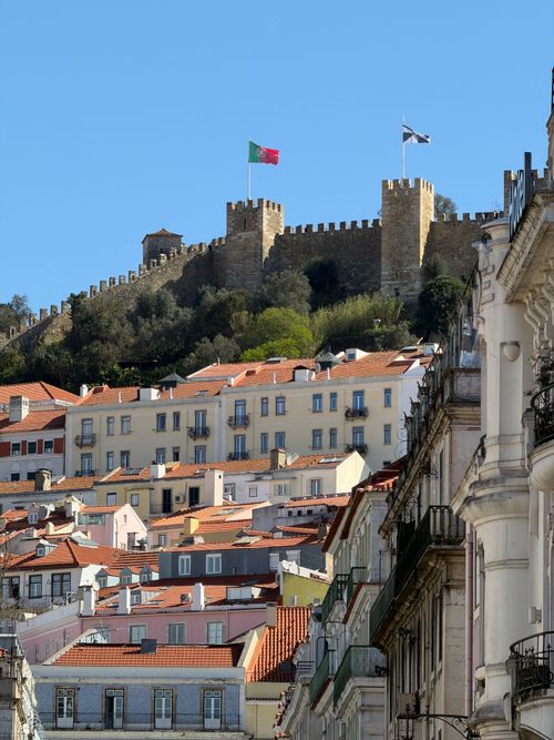 Gratis Veduta panoramica del Castello di São Jorge con l'architettura tradizionale di Lisbona in primo piano, sotto un cielo azzurro e limpido. Foto a disposizione