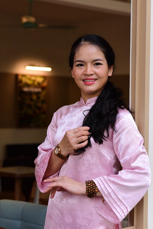 Free Confident woman in a pink traditional dress smiling indoors with warm lighting. Stock Photo