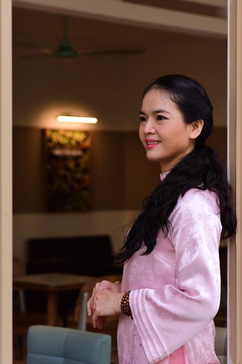 Free A woman wearing a pink traditional dress smiling elegantly indoors. Stock Photo