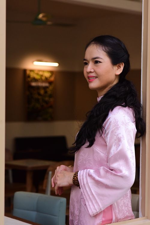 Free Elegant woman in traditional pink clothing stands thoughtfully by a window indoors. Stock Photo
