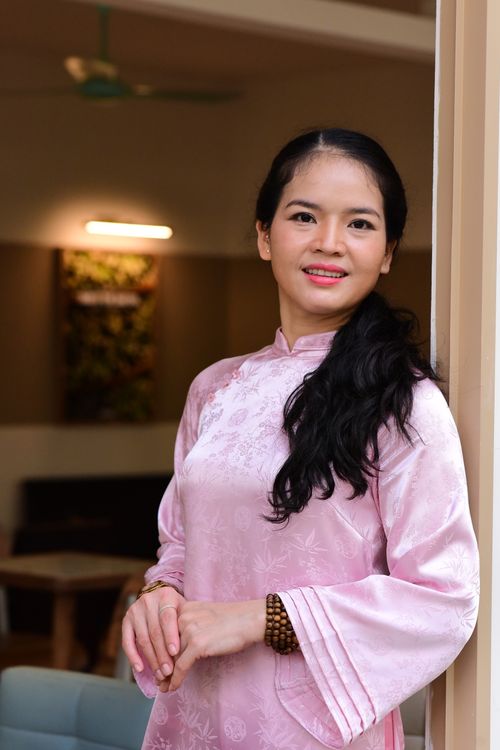 Free Woman in a pink traditional dress standing indoors with a serene smile. Stock Photo