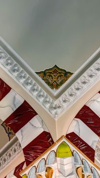 Detailed view of a mosque's ornate ceiling with colorful patterns and arches.