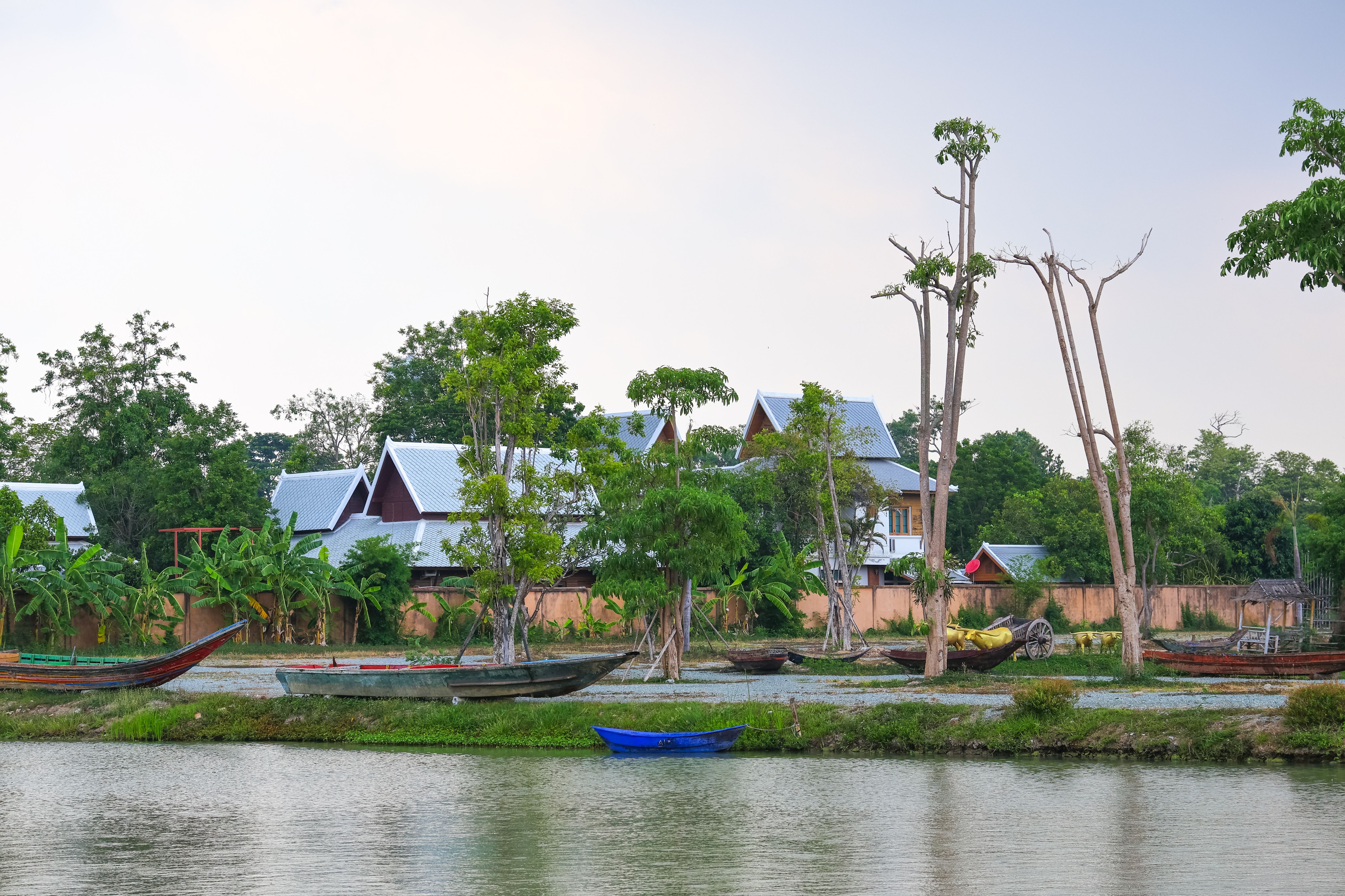 Serene riverside scene with traditional boats and lush greenery in Chonburi, Thailand