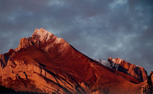 Rough mountain ridge against overcast sky during sundown