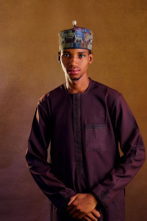 Free An adult male in traditional attire, wearing a decorative cap, poses indoors. Stock Photo