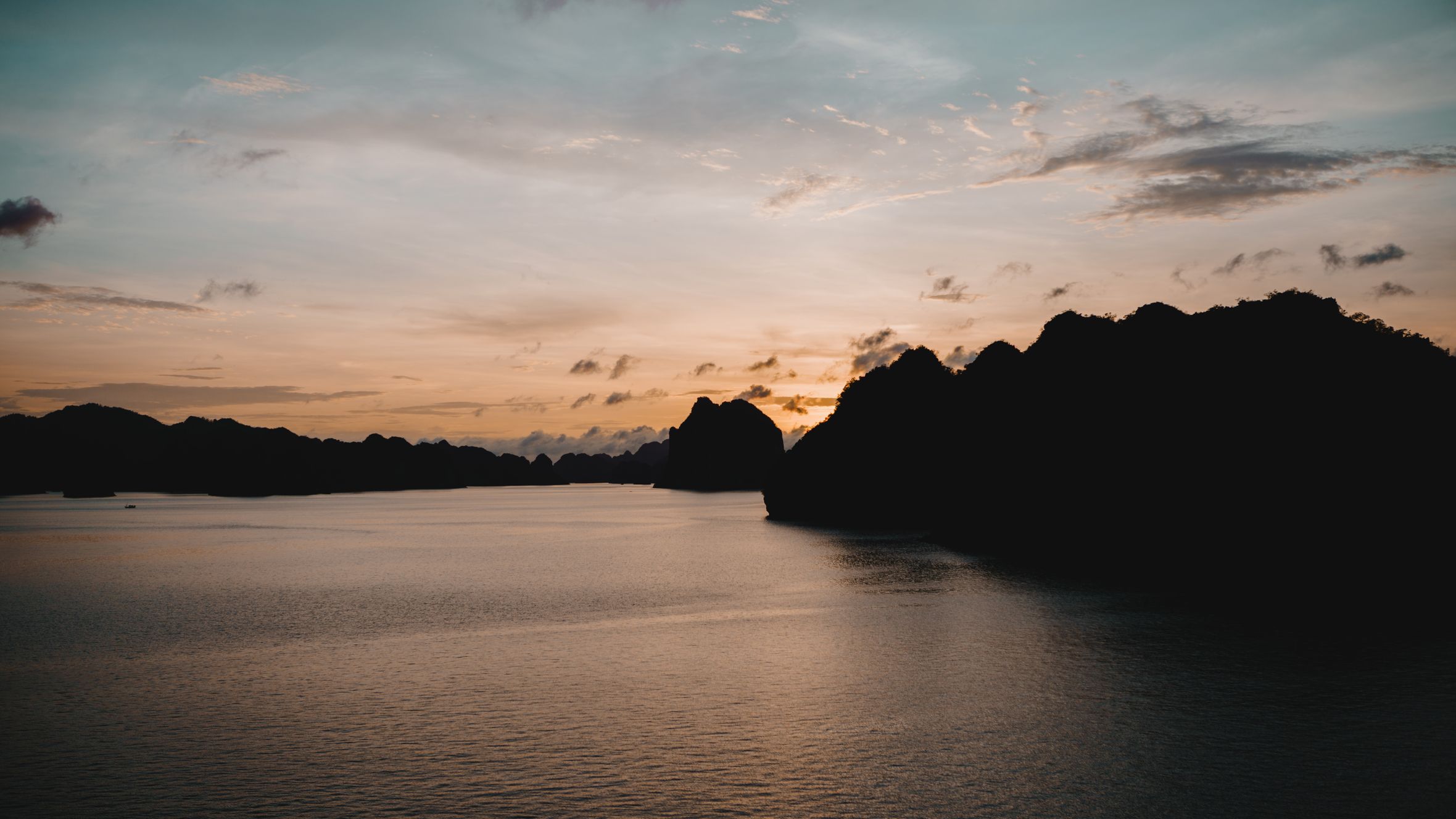 Tranquil sunset over Halong Bay, Vietnam with silhouette of limestone islands.