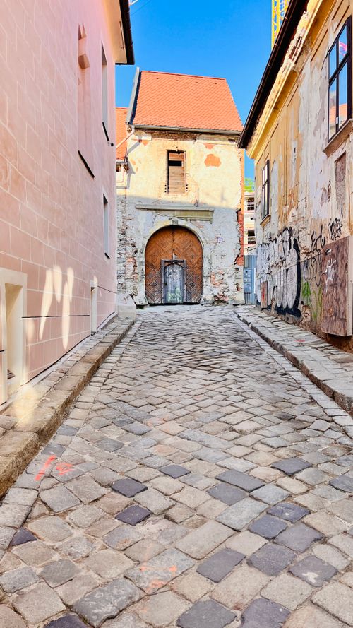 Free Sunlit cobblestone alley between old buildings in a historic town, showcasing urban decay and charm. Stock Photo