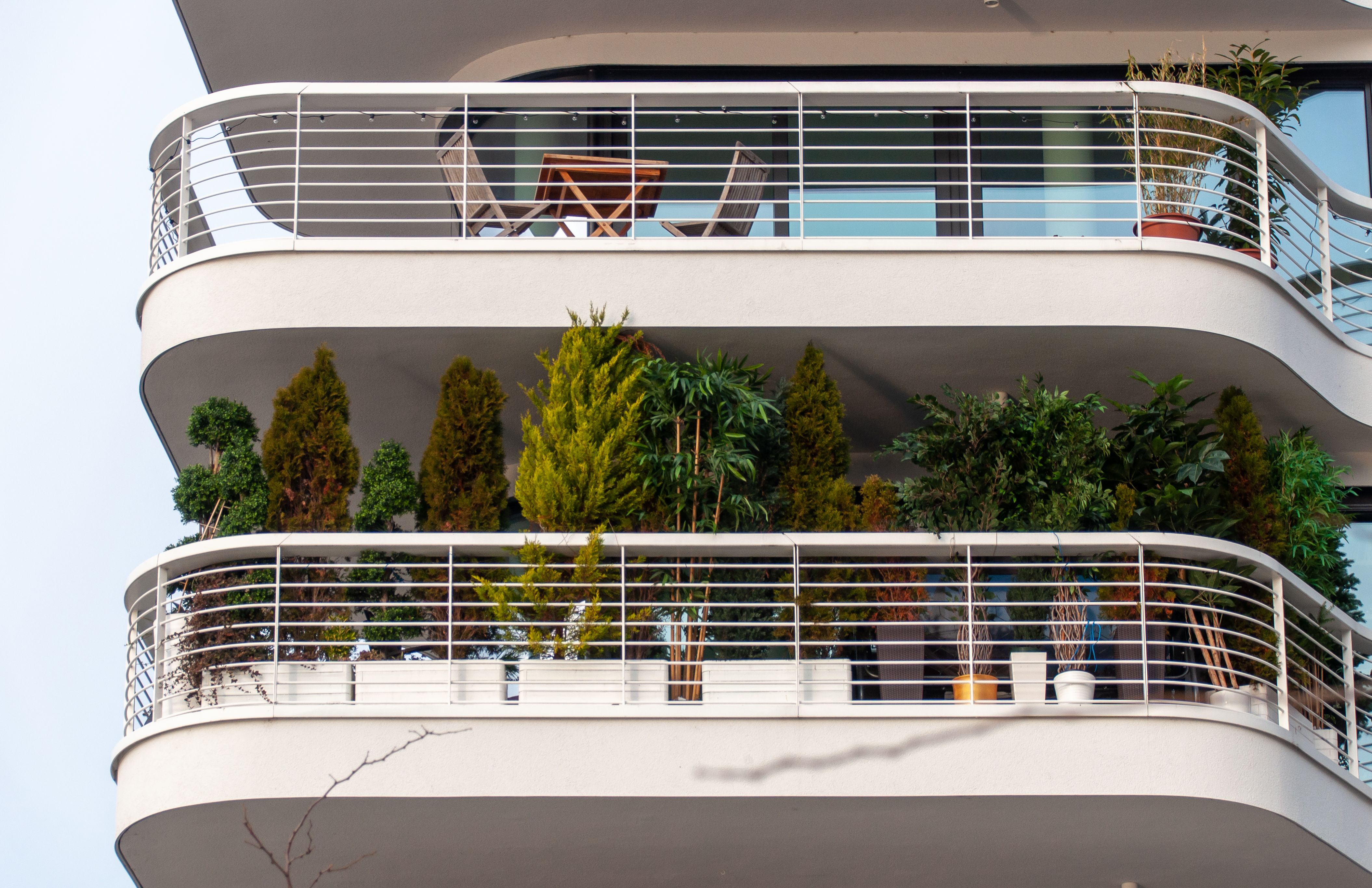 Compact plant stand on a narrow balcony with outdoor furniture and storage