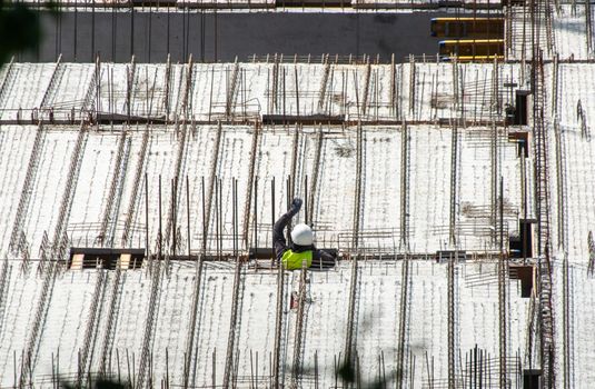 Aerial view of a construction worker on a building site, showcasing a structural framework with rebar.