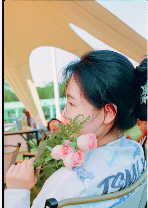 Free Young woman outdoors holding a bouquet of pink roses, enjoying a sunny day. Stock Photo