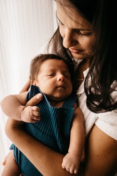 一位母亲慈爱地抱着她刚出生的婴儿，温柔与母性自然流露