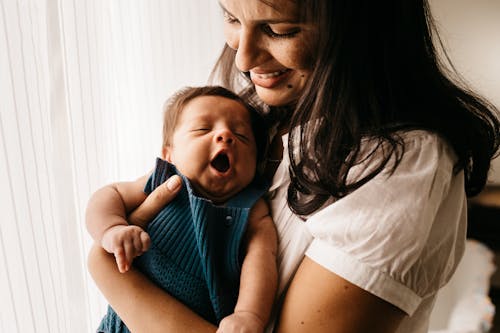 Foto Close Up Ibu Yang Tersenyum Menggendong Bayinya Yang Lucu