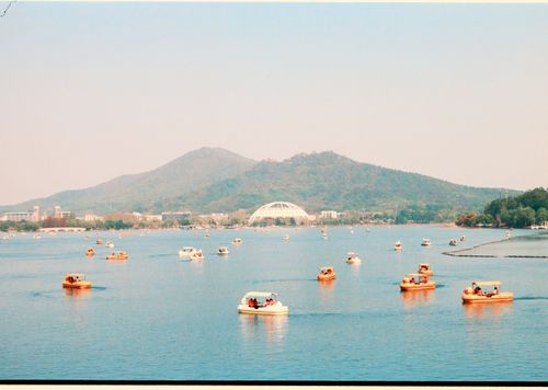 Free Peaceful lake with boats against a mountain backdrop under a clear sky. Stock Photo