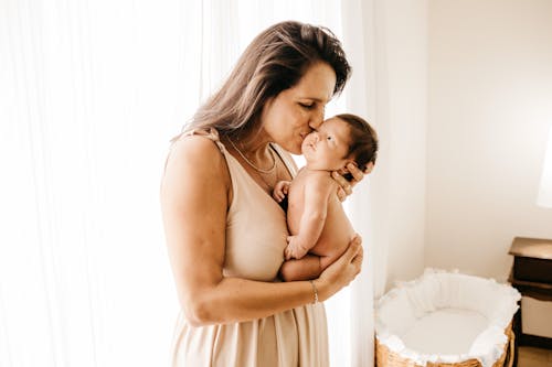 赤ちゃんを運んでキスする女性の側面写真