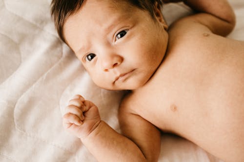 Free ベッドに横たわっているトップレスの赤ちゃんのクローズアップ写真 Stock Photo