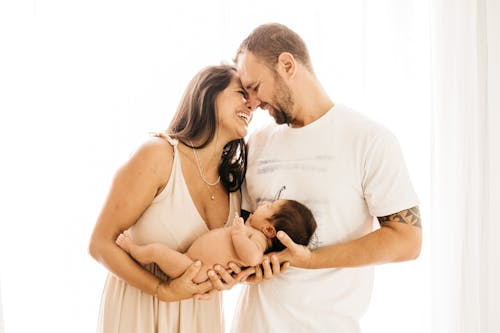 Free Photo of Laughing Couple Carrying a Baby Stock Photo