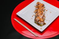 白色盘子里，顶视图下的美味寿司卷配着酥脆浇头，堪称完美的食物摄影