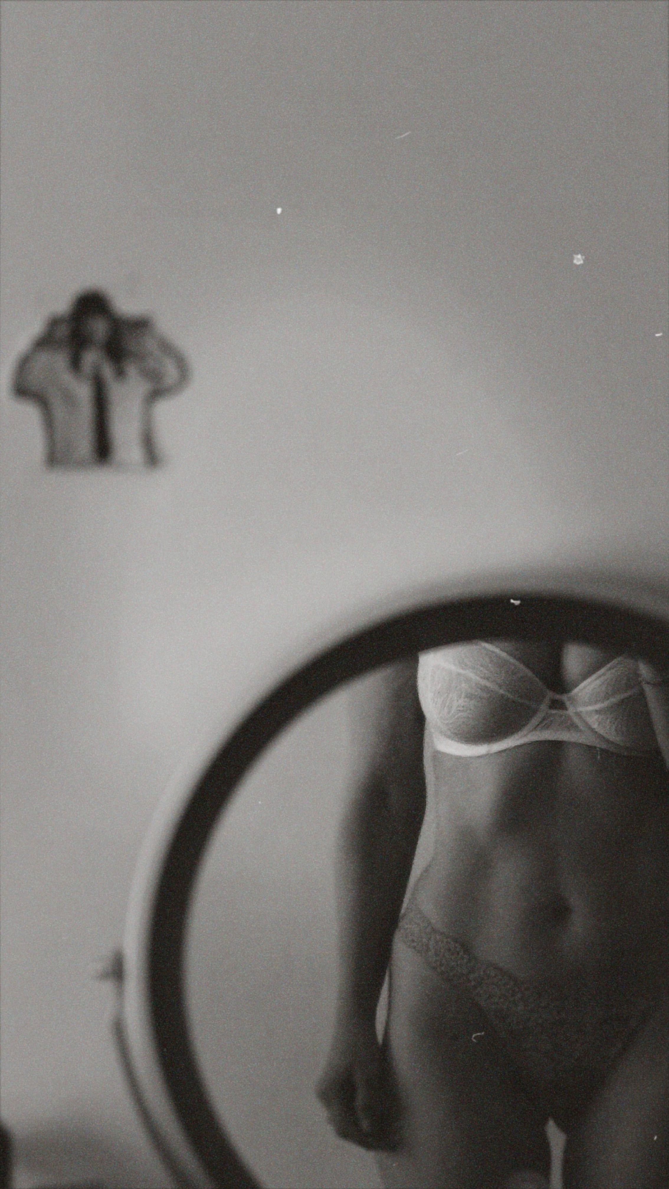 Elegant black and white photo capturing a partial reflection of a person in lingerie, adding an artistic and mysterious feel.