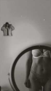 Elegant black and white photo capturing a partial reflection of a person in lingerie, adding an artistic and mysterious feel.
