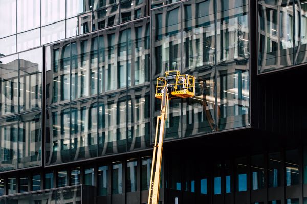 Workers on lift cleaning glass building exterior
