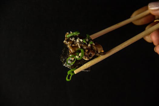A delectable sushi piece garnished with toppings held by chopsticks.