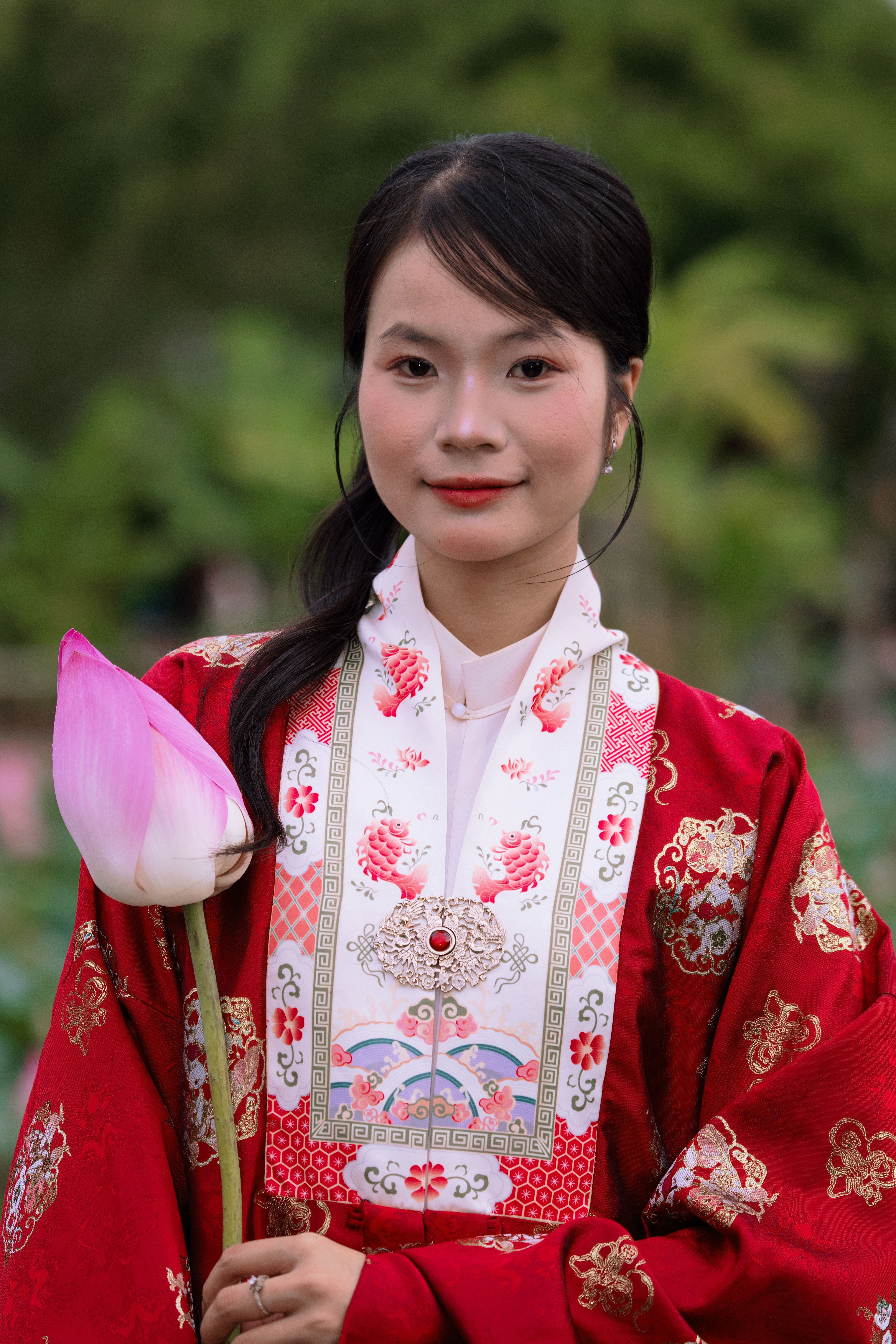 Elegant portrait of a woman in traditional Asian attire holding a pink lotus flower.