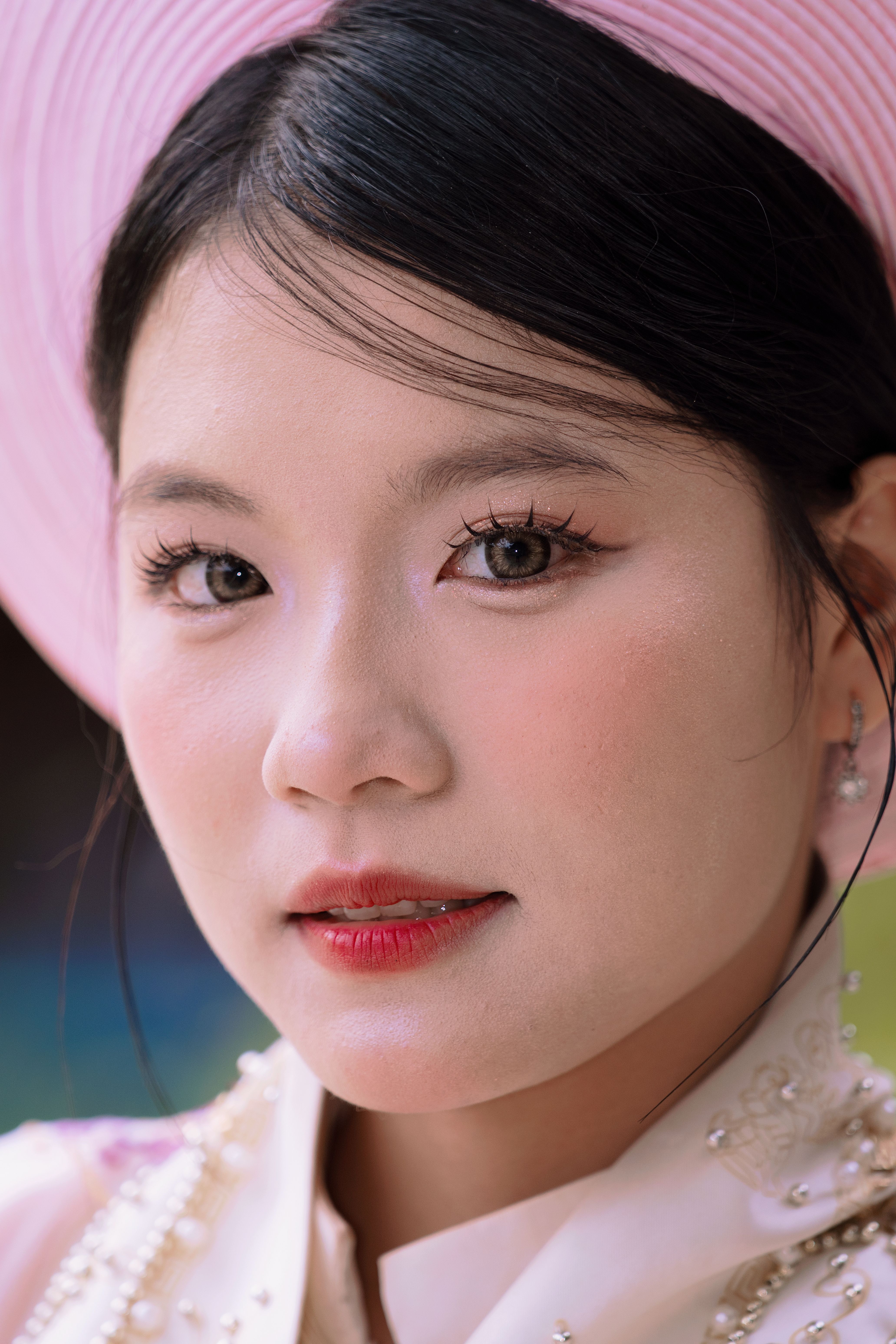 Close-up portrait of a woman wearing pink traditional clothing and hat, showcasing elegance and beauty.