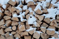 砍好的原木高高堆积，白雪覆盖其上，唤起冬日的温暖