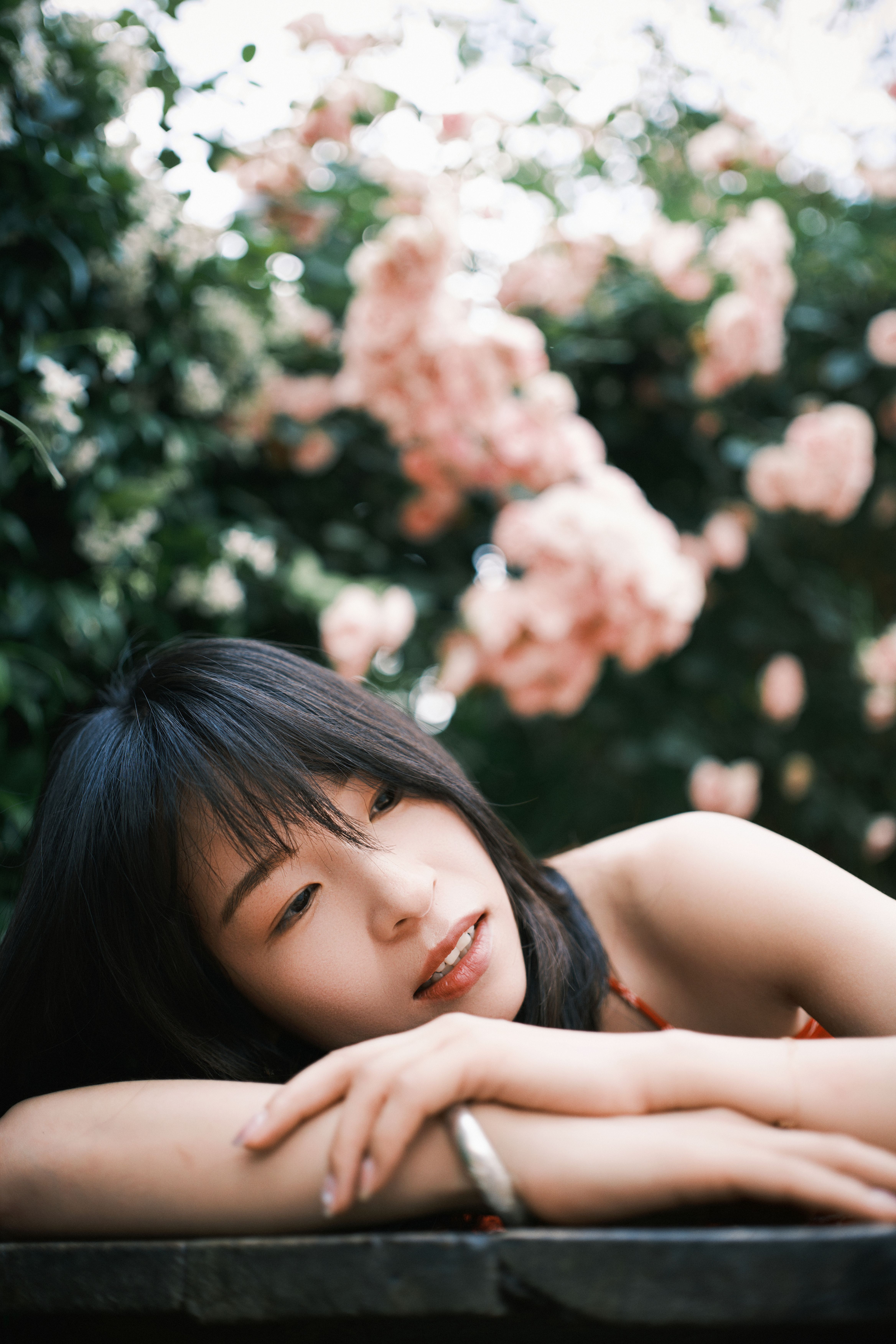 A serene portrait of a woman lying on her arms amidst blooming flowers, capturing tranquility and natural beauty.