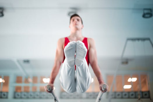A male gymnast demonstrates strength and balance on parallel bars indoors.