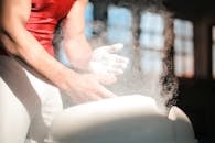 Crop male gymnast in sportswear rubbing hands with dry spots magnesium powder while preparing for exercises
