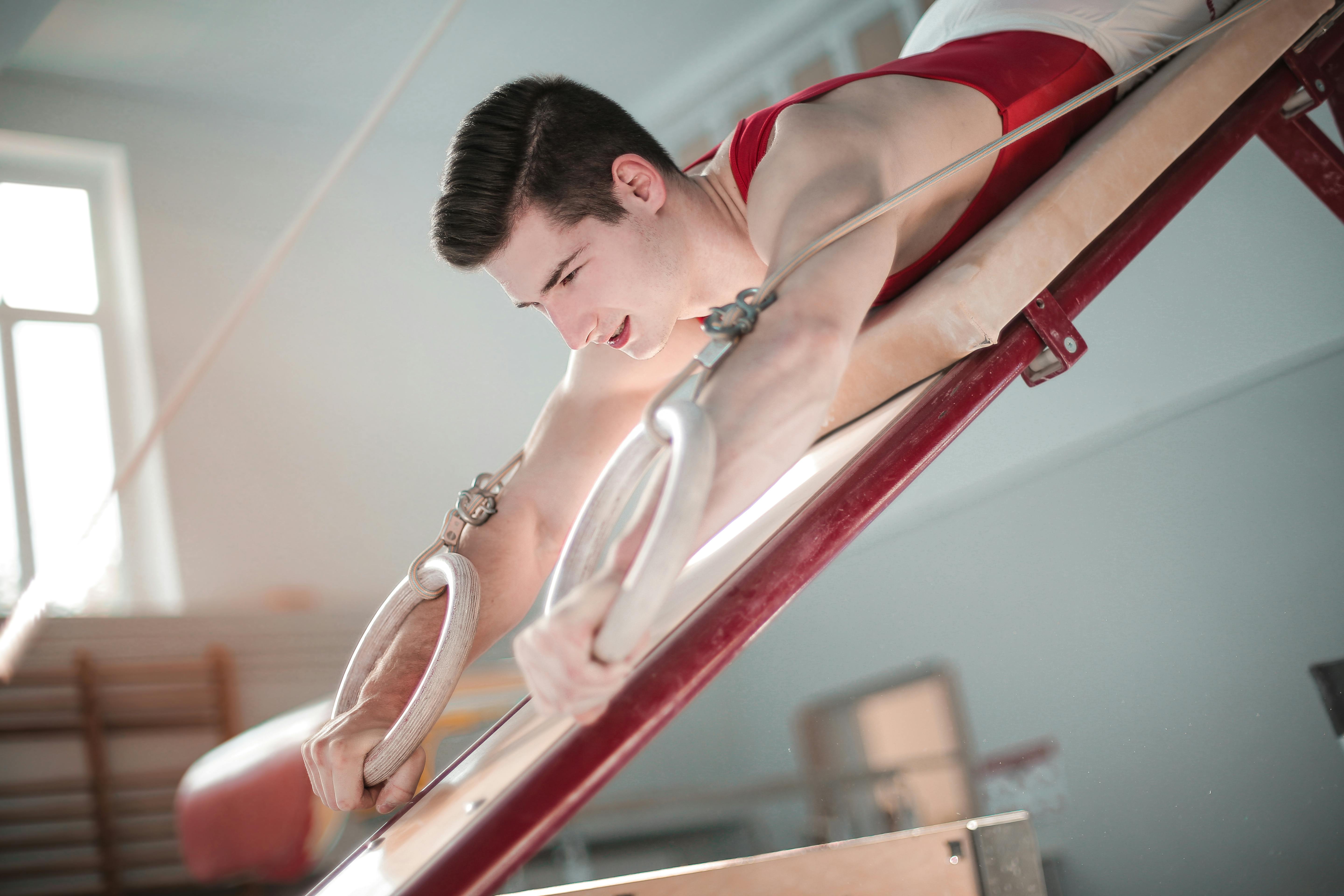 Young male gymnast training on parallel bars indoors, showcasing strength and balance.