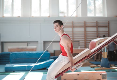 Jonge Sportman Zittend Op Gymnastiek  Apparatuur