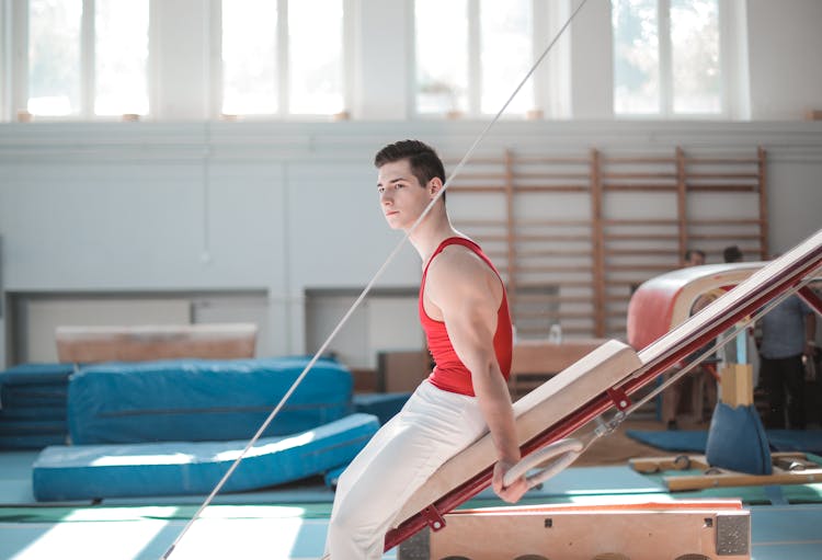 Young Sportsman Sitting On Gymnastic Equipment