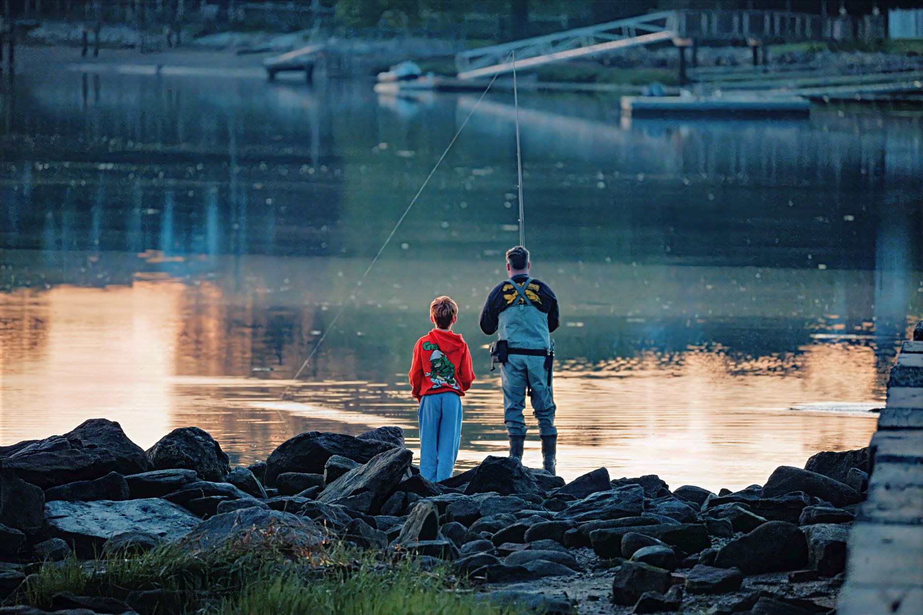 A serene view of a father and son fishing at dawn in Stamford, Connecticut.