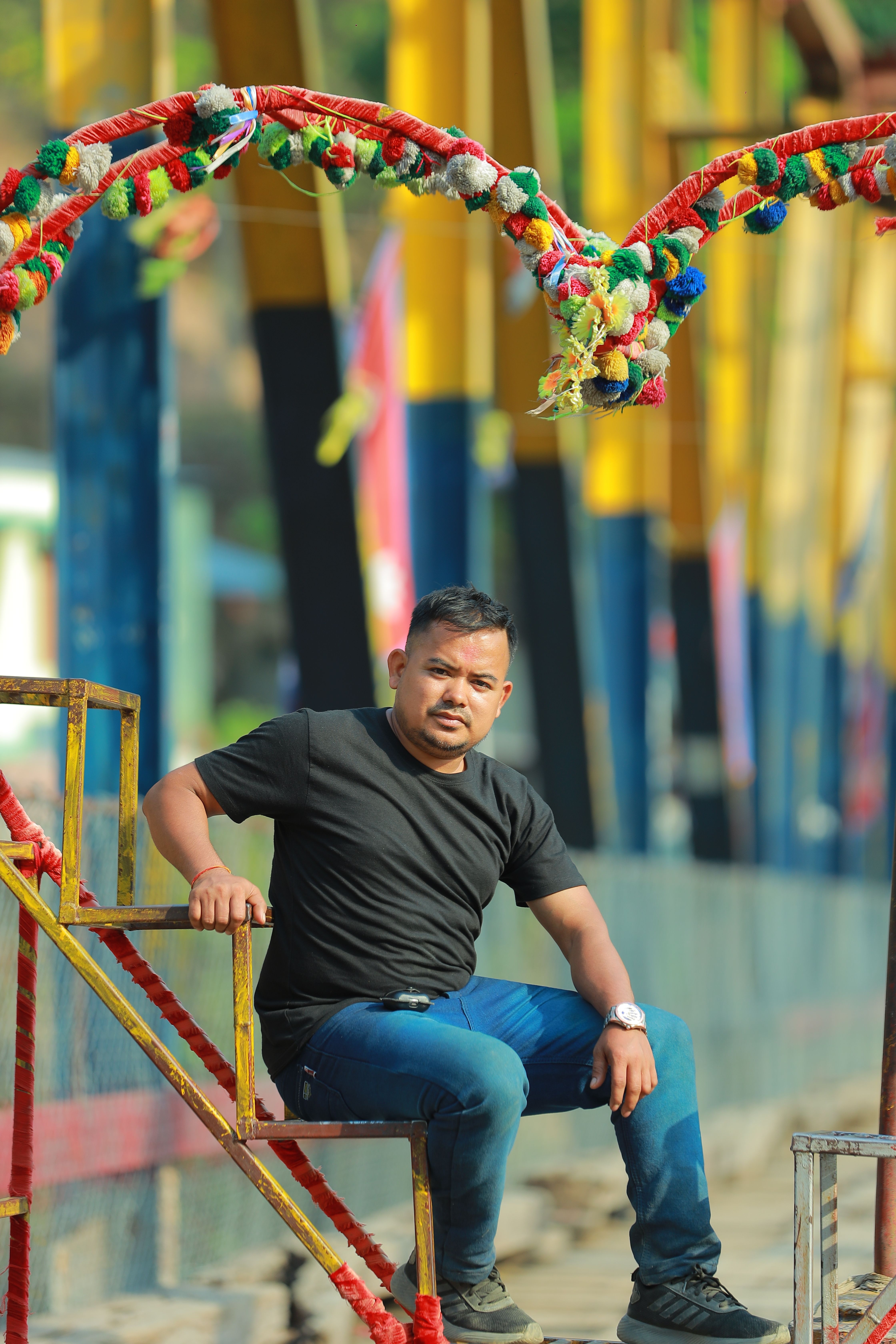 Casual man sitting on a vibrant amusement park ride on a sunny day.
