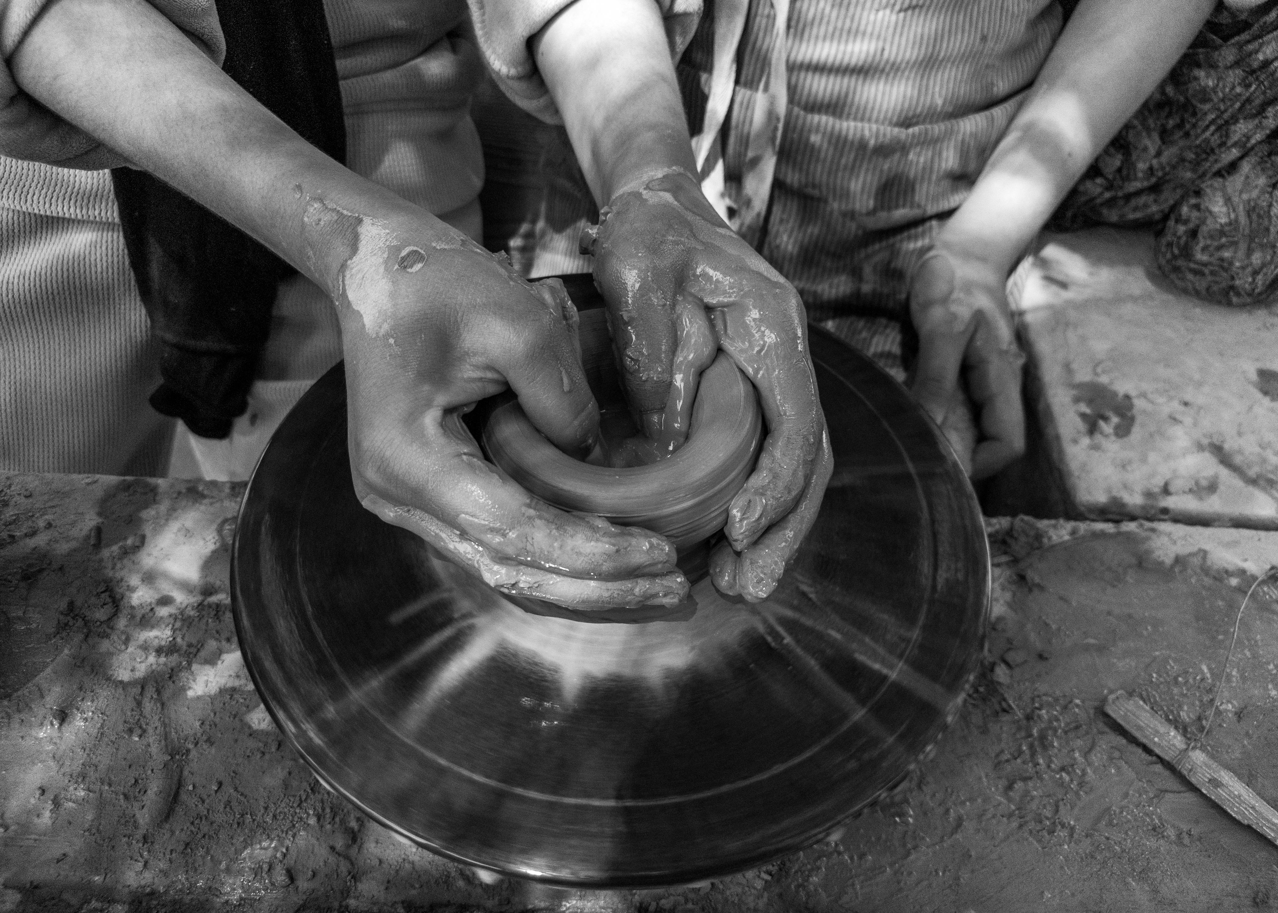 Close-up of hands shaping clay on a pottery wheel outdoors in Faiyum, Egypt.